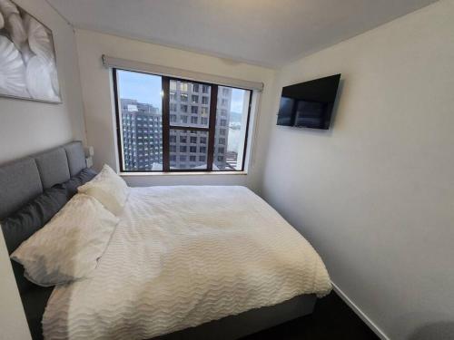 a bedroom with a bed and a large window at Cosy studio in the heart of the city in Wellington