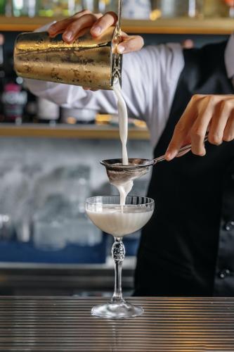 a bartender pouring a drink into a martini glass at Hotel Mary in Vico Equense
