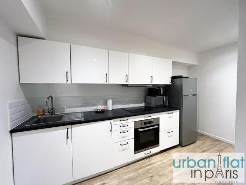 une cuisine avec des armoires blanches et un réfrigérateur en acier inoxydable dans l'établissement Urban Flat 185 - Pretty 2 Bedroom Apartment in Paris, à Paris