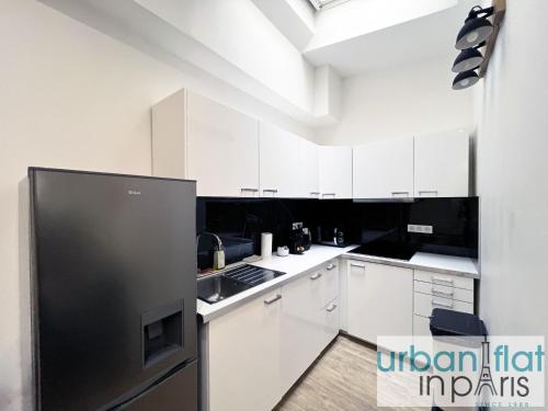 une cuisine avec des armoires blanches et un réfrigérateur en acier inoxydable dans l'établissement Urban Flat 187 - Sublime 1 Bedroom in Paris, à Paris