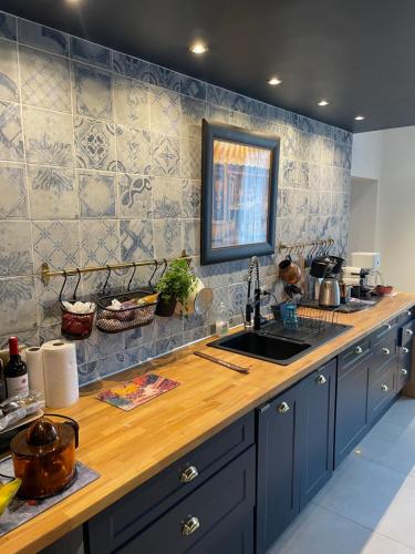 une cuisine avec des placards bleus et un comptoir en bois dans l'établissement Villa Ô Room, à Chasnay