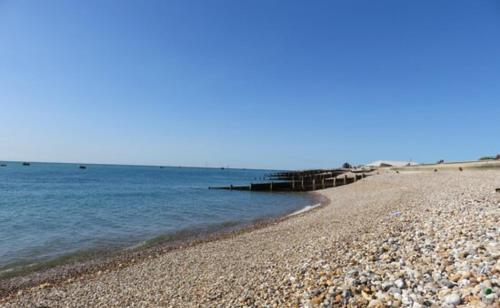 a rocky beach with a pier in the water at Little Spain in Selsey