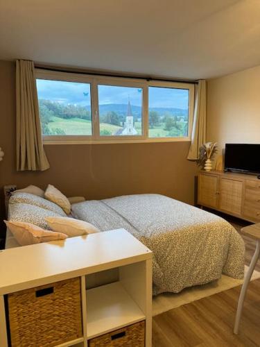 une chambre avec un lit et une table et deux fenêtres dans l'établissement Studio cosy au cœur du Haut-jura, à Foncine-le-Bas