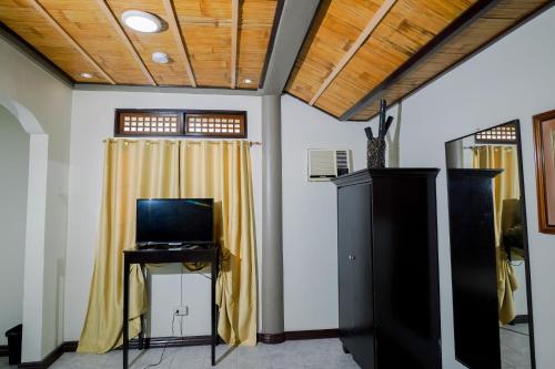 a room with a television and a table with a yellow curtain at Casa Basilisa Hotel & Resort in Guinobatan