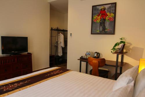 a bedroom with a bed and a dresser and a television at Nam Bo Boutique Hotel in Can Tho