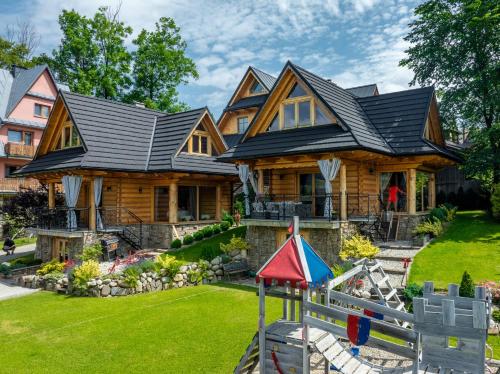 a log home with a playground in front of it at Zacisze Galicove in Zakopane