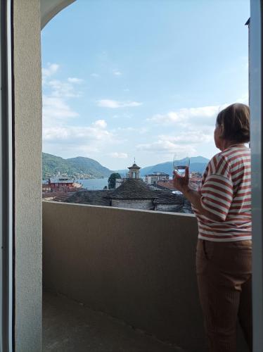 a woman standing on a balcony drinking a glass of wine at Lago d'Orta attico Sofia in Omegna