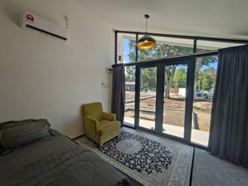 a bedroom with a bed and a chair and a window at Secotek Nenasi Chalet in Pekan