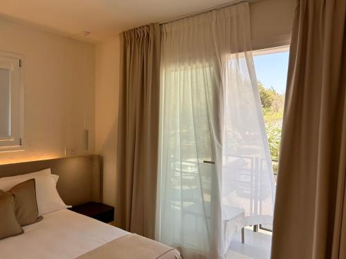 a bedroom with a bed and a large glass window at Vireo Rooms in Santa Maria Navarrese