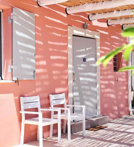 two chairs and a table on the porch of a pink house at Joanna Deluxe Apartments in Kynopiástai