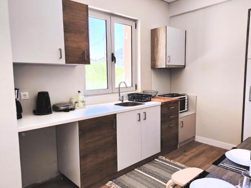 a kitchen with white cabinets and a sink and a window at Joanna Deluxe Apartments in Kynopiástai