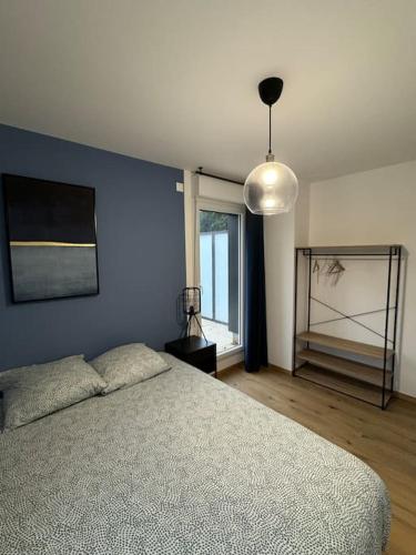 Un dormitorio con una cama y una pared azul. en Le Contrie - Bel appartement avec terrasse, en Nantes