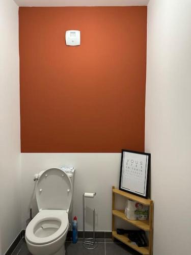 baño con aseo blanco y pared de color naranja en Le Contrie - Bel appartement avec terrasse, en Nantes