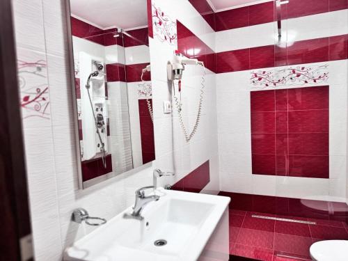 a red and white bathroom with a sink and a mirror at Hanul Domnesc Imperial Hotel & SPA in Călan