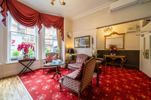 a living room with chairs and a red rug at Hotel La Place in London