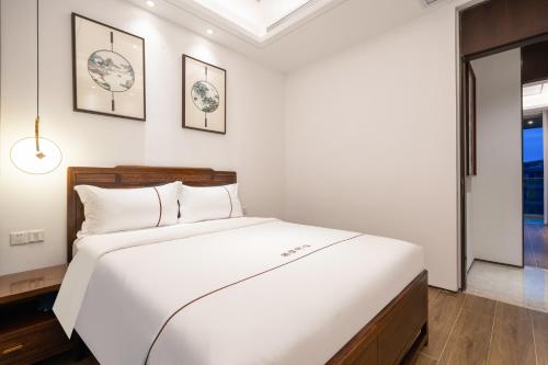 a bedroom with a white bed and two pictures on the wall at Sanya Haitang Bay Muyu Time Seaview Apartment in Sanya