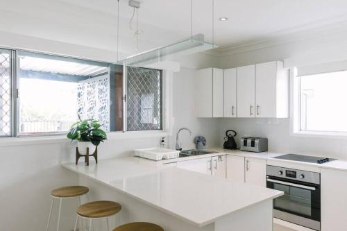 a kitchen with white cabinets and a white counter top at Miami's Family Getaway Sleeps 10, Pool, Patio, Walk to North Burleigh Beach & Shops in Gold Coast