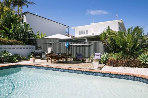 a swimming pool with a table and chairs next to a house at Miami's Family Getaway Sleeps 10, Pool, Patio, Walk to North Burleigh Beach & Shops in Gold Coast
