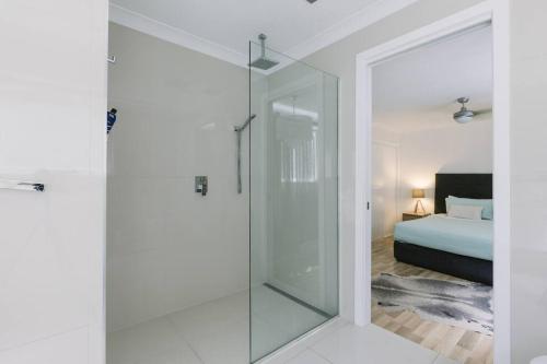a glass shower door in a bedroom with a bed at Miami's Family Getaway Sleeps 10, Pool, Patio, Walk to North Burleigh Beach & Shops in Gold Coast