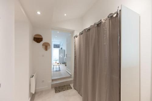une salle de bain avec un rideau de douche et un couloir dans l'établissement Appartement entièrement neuf avec terrasse privative !, à Mulhouse
