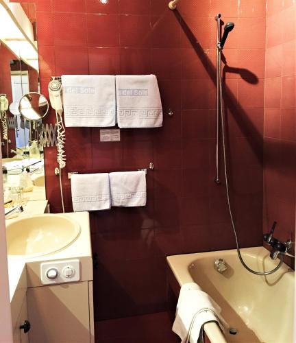 a red bathroom with a sink and a tub and a mirror at Hotel Garni Villa del Sole in Ponte Tresa