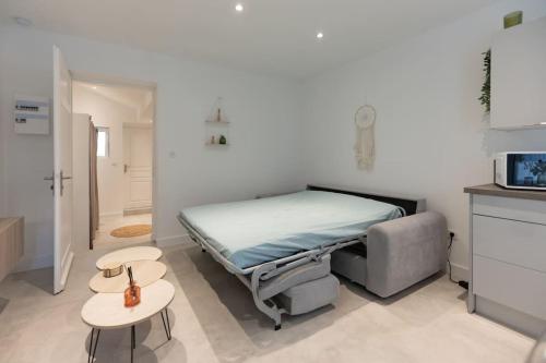 une chambre avec un lit et deux tables et un micro-ondes dans l'établissement Appartement entièrement neuf avec terrasse privative !, à Mulhouse