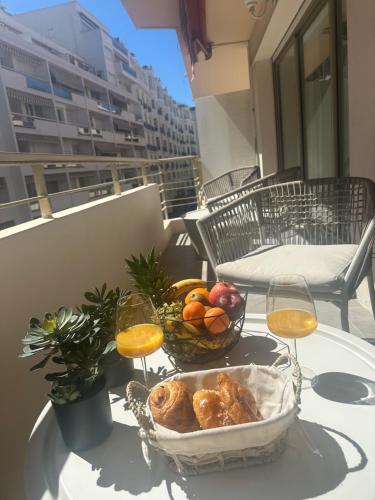 a table with a bowl of fruit and two glasses of wine at T3Appartement de luxe Croisette en face de la plage Martinez 80m2 in Cannes