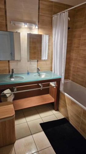 une salle de bain avec un lavabo et une baignoire dans l'établissement Appartement au golf des fontenelles, à LʼAiguillon-sur-Vie