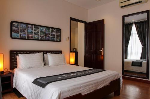 a bedroom with a large bed and a mirror at Nam Bo Boutique Hotel in Can Tho