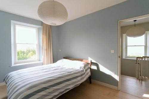 a bedroom with a bed and two windows at 1 Avonside, Bantham with sea views in Bantham