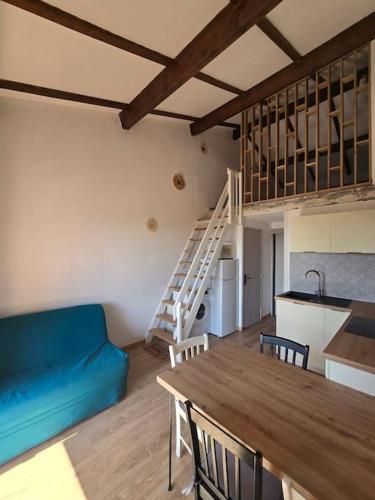 un salon avec une table et un canapé bleu dans l'établissement Appartement Duplex proche de la mer, à Saint-Cyprien