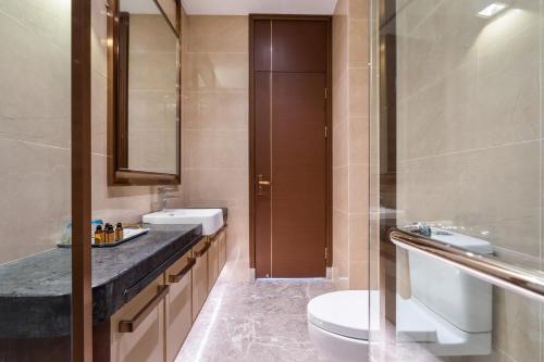 a bathroom with a toilet and a sink at Sanya Haitang Bay Muyu Time Seaview Apartment in Sanya