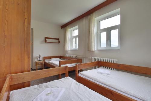 a room with two beds and two windows at Horský hotel Žižkova bouda in Pec pod Sněžkou
