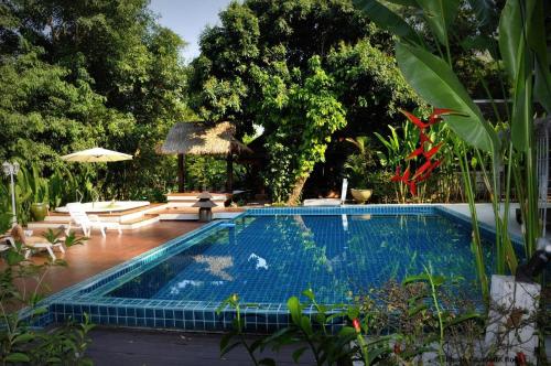 a swimming pool in a yard with trees at Tonnam Homestay in Chiang Mai