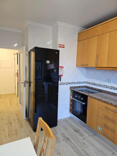 a kitchen with a black refrigerator and wooden cabinets at Ideal Bubble House in Faro