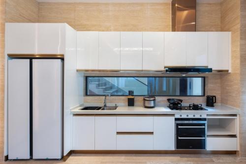 a kitchen with white cabinets and a sink at Sanya Haitang Bay Muyu Time Seaview Apartment in Sanya