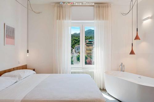 a white bedroom with a tub and a large window at Affittacamere Isabella, Terre Marine in Levanto