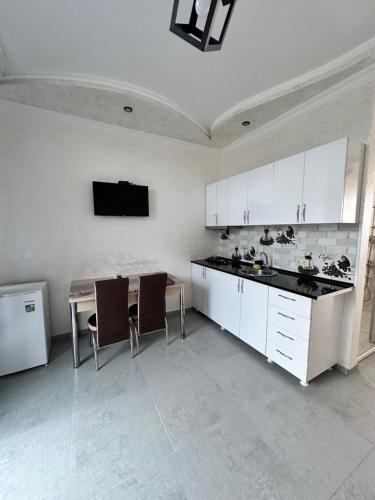 a kitchen with white cabinets and a table and chairs at Hotel black sea in K'obulet'i