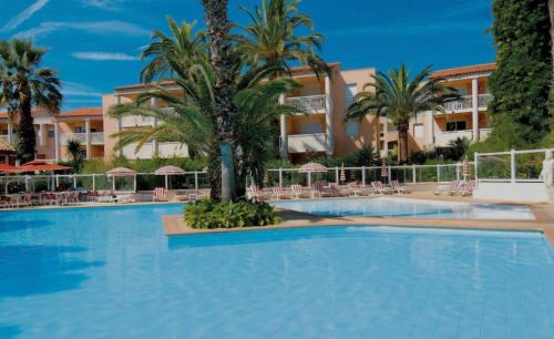 une grande piscine avec des palmiers en face d'un bâtiment dans l'établissement Appartement T2 avec piscine mer, à Vallauris