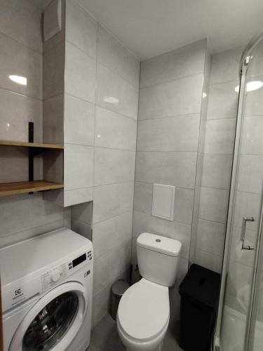 a bathroom with a toilet and a washing machine at Mieszkanie 11 Listopada in Konin
