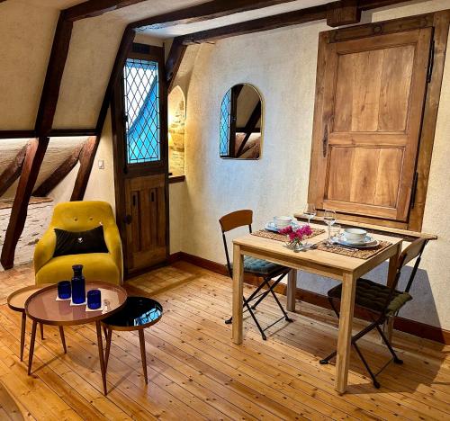 a dining room with a table and a yellow chair at Le Petit Tinténiac - T2 cosy au cœur de la Doutre in Angers