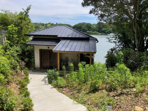 a house with a black roof next to a lake at やどかり志摩の隠れ家 in Shima