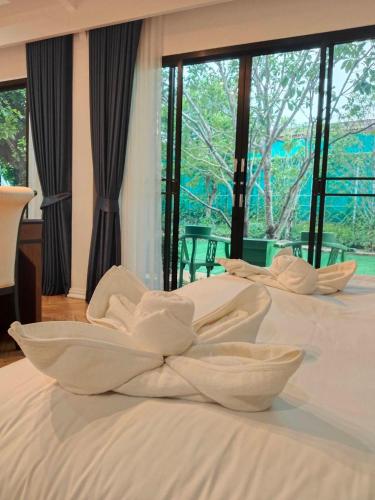 two beds with white sheets on them in a bedroom at โรงแรม ดิ โอวาเล่ย์ [The O Valley Boutique Hotel] in Ban Tha Phala Nua