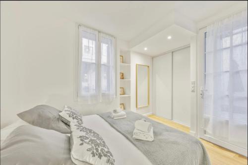 une chambre blanche avec un lit avec deux serviettes dessus dans l'établissement Suquet Perrissol, à Cannes