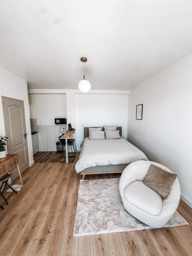 une chambre blanche avec un lit et une chaise dans l'établissement Logement très chaleureux à Marseille, à Marseille