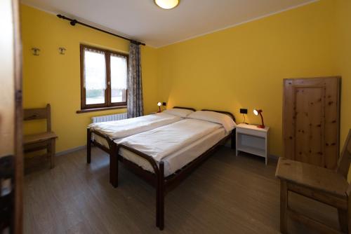 um quarto com uma cama grande e paredes amarelas em Appartamento Baita Cusini Saroch em Livigno