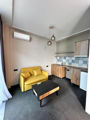 a living room with a yellow couch and a kitchen at Hotel black sea in K'obulet'i