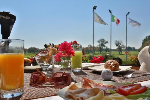 a table with a plate of food and a glass of orange juice at Isola di Albarella Golf Hotel in Isola Albarella