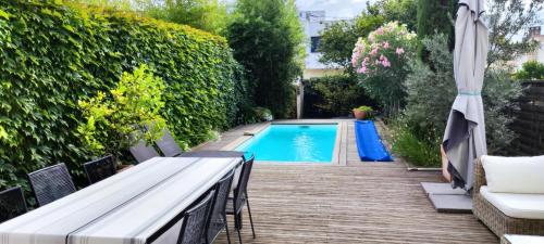 une piscine dans le jardin avec une table et un parasol dans l'établissement Maison de ville style échoppe, à Le Bouscat