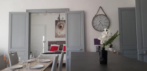 a dining room with a table and a clock on the wall at Cosy 4 minutes à pieds du centre historique avec parking in Montluçon